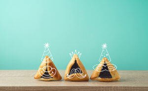 Jewidh holiday Purim concept with cute hamantaschen cookies characters on wooden table